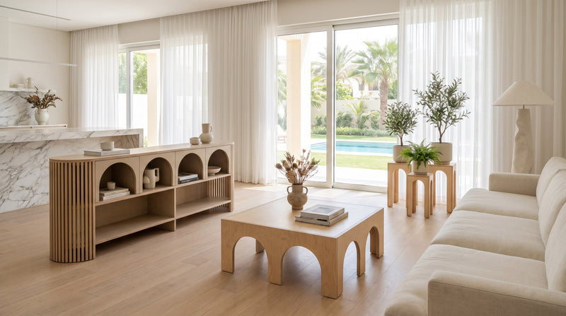 Render: an open-plan Dubai villa living room with marble, sheer curtains and glass doors onto the garden and pool, a Jeffrey Sideboard, Luna Coffee Table and Plant Stands Petite in Natural birch plywood