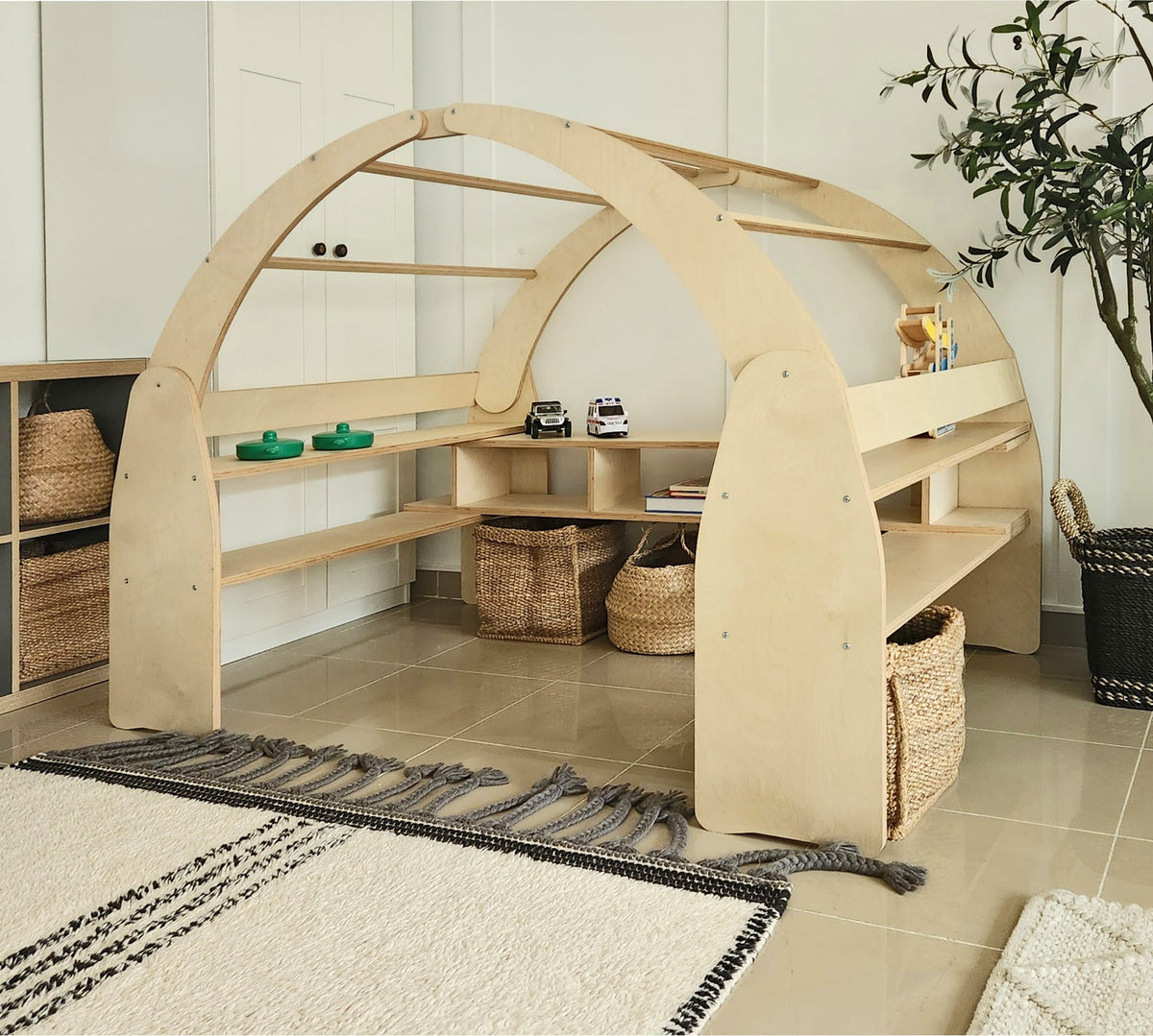 Ply Arch, a large birch plywood climbing and reading arch with rungs and built-in shelves in a Dubai playroom, made by Plyconcept