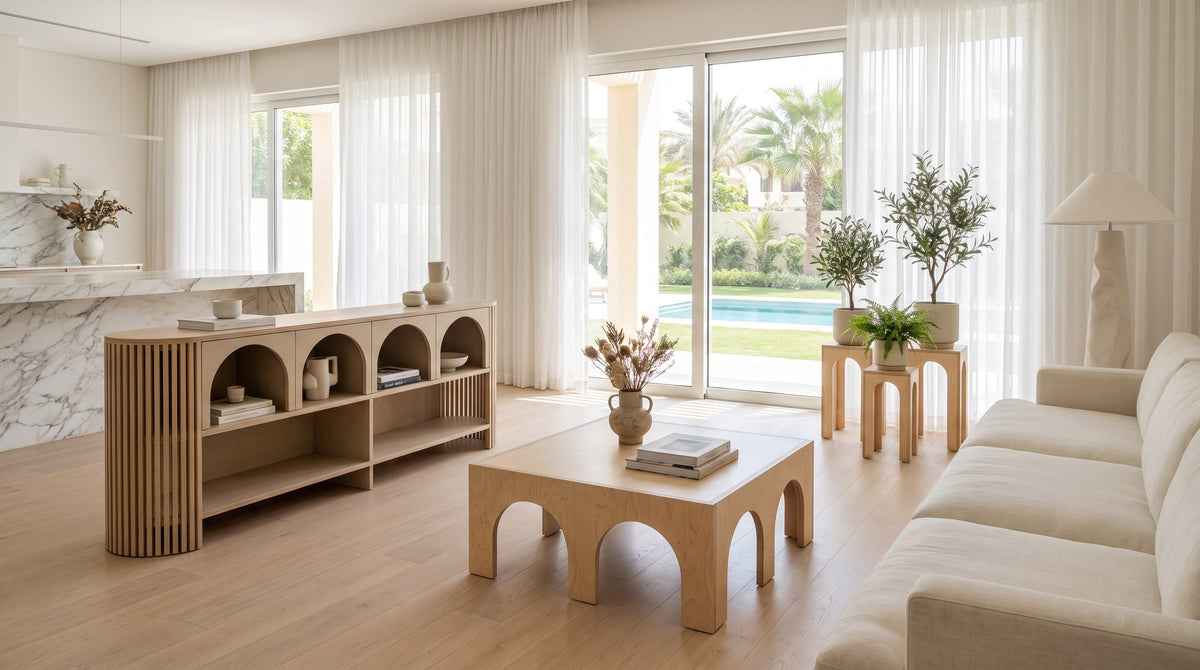 Render: an open-plan Dubai villa living room with marble, sheer curtains and glass doors onto the garden and pool, a Jeffrey Sideboard, Luna Coffee Table and Plant Stands Petite in Natural birch plywood
