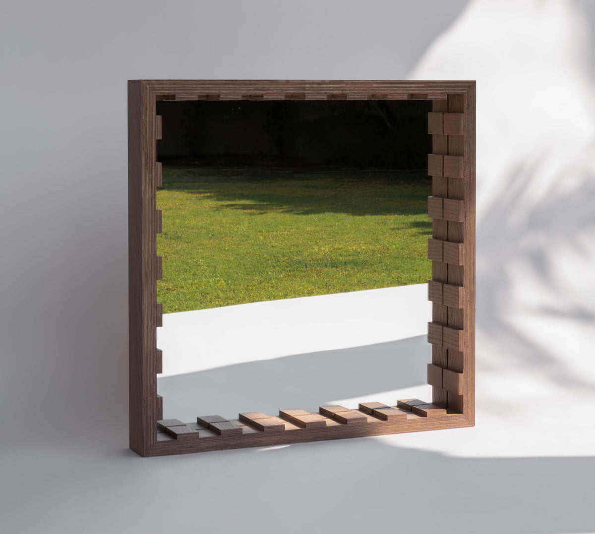 Sarab mirror framed in oak plywood in the Sand finish, hung on a pale wall to bounce light across a Dubai living room, a limited edition by Plyconcept