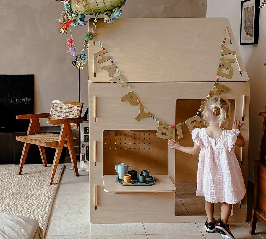 A child at the Ply House, a birch plywood play house, set up for a birthday