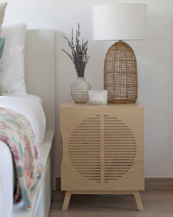 Penelope Bedside Table in birch plywood beside a bed, with a rattan lamp — handmade in Dubai by Plyconcept