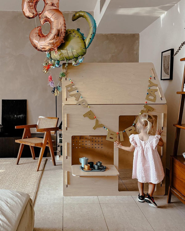 A child playing at the Ply House, a birch plywood play house, at home on a birthday