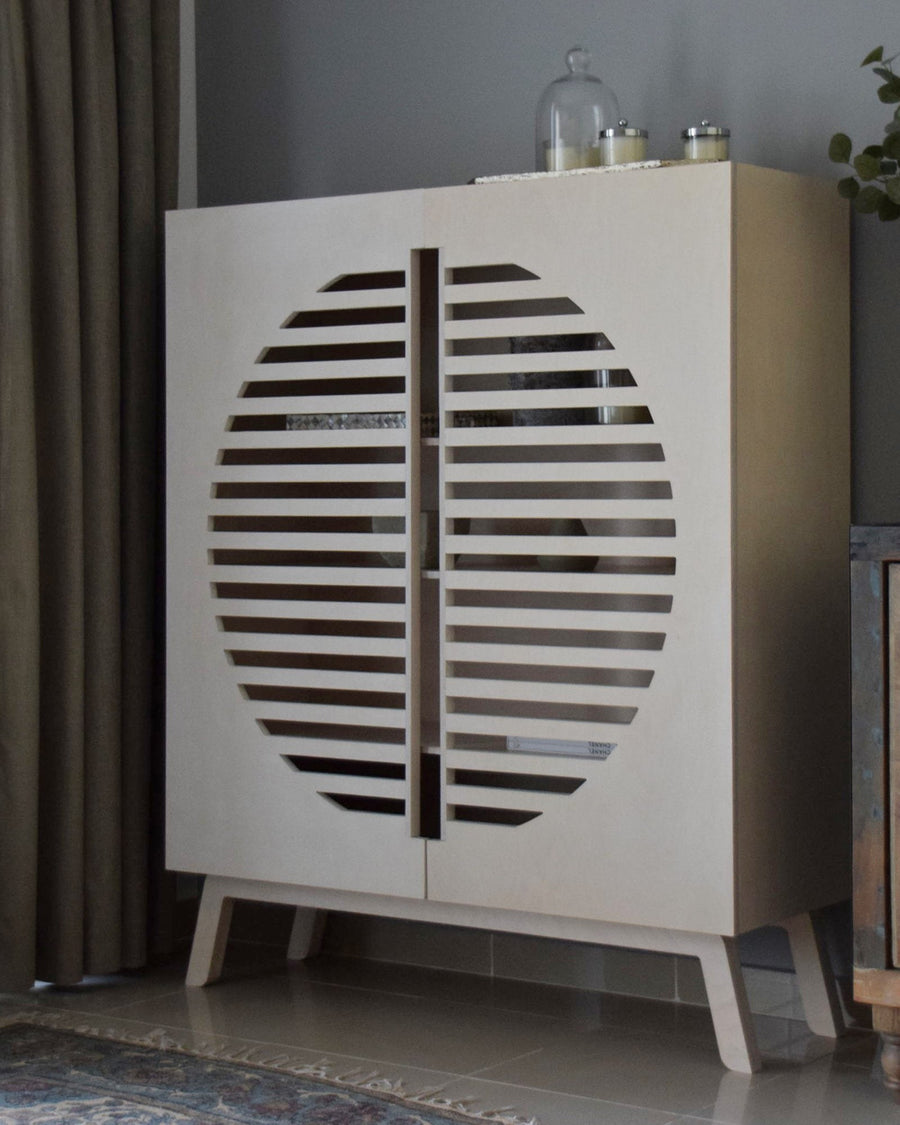 Zoe Side Cabinet in birch plywood, a circle of slots across its two doors, styled with a plant